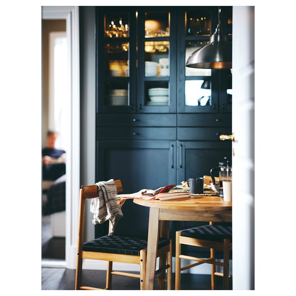 Cosy dining nook with wooden NACKANÄS table, black chairs, dark blue cabinets, and coffee setup.