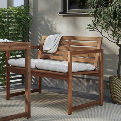 Two light brown wood outdoor chairs with white cushions, one with a blanket.