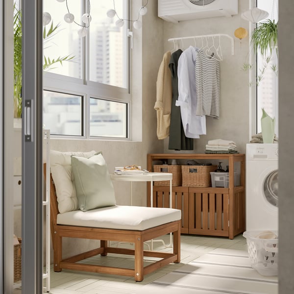 Laundry room with NÄMMARÖ wooden chair, beige cushions, clothesline, white washing machine, and tidy shelf with baskets and plants.