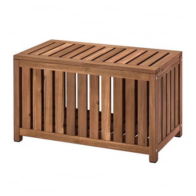 An outdoor NÄMMARÖ storage box made of brown acacia wood with a slatted design for ventilation and dual functionality as seating.