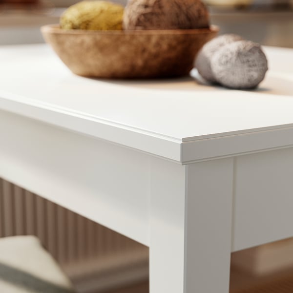 Close-up of white NÄSINGE table edge, smooth finish, modern design. Bowl with fruits on top, showcasing durability and clean lines.