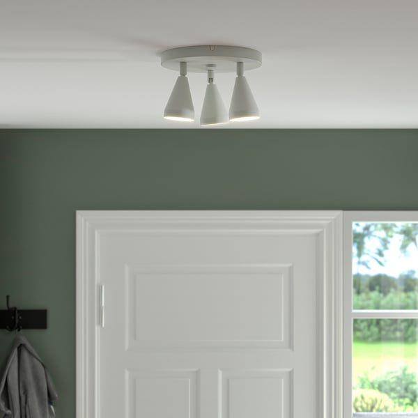 Three adjustable ceiling spotlights, part of the NÄVLINGE series, mounted above a white door in a green room, providing focused lighting.