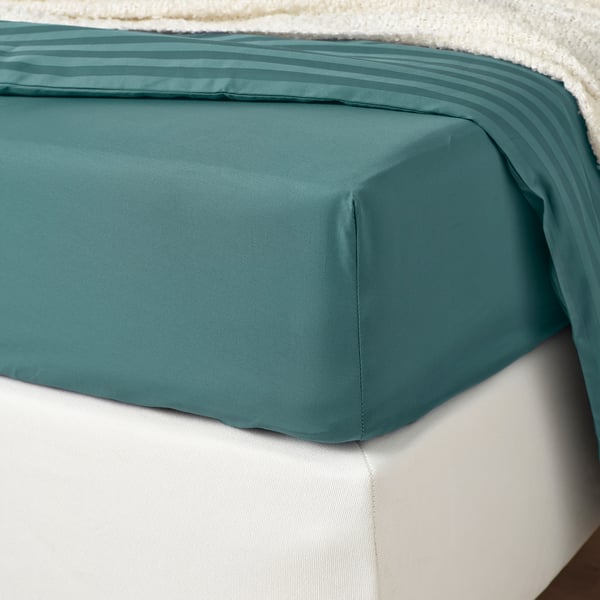 A fitted sheet in blue-green, silky and smooth, shown on a mattress.