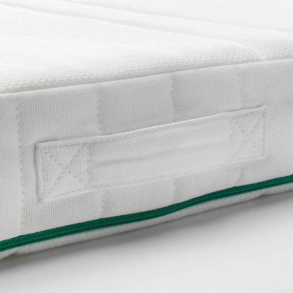 Close-up of a white mattress corner with green edge, showcasing quilted design for comfort.