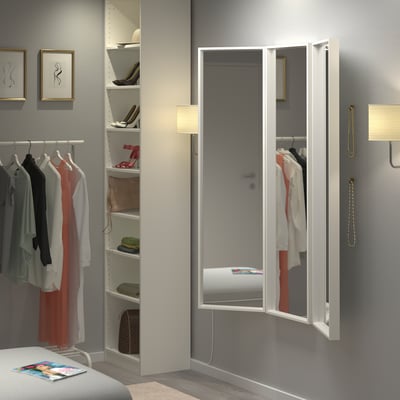 Tri-fold NISSEDAL mirrors in bedroom reflecting closet and shelves, enhancing space and appearance.
