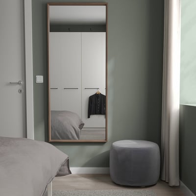Minimalist bedroom with NISSEDAL mirror, bed, ottoman, muted green walls, closet.