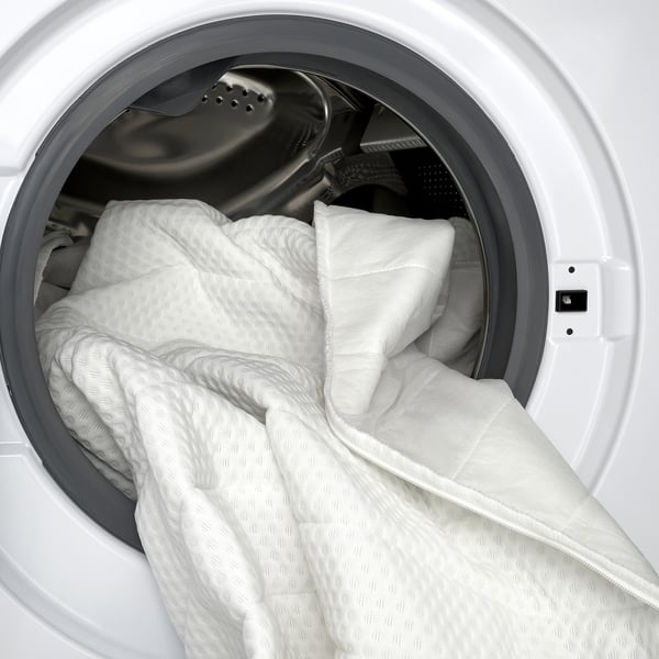 Washing machine with white, textured mattress pad, cover removed, ready for wash.