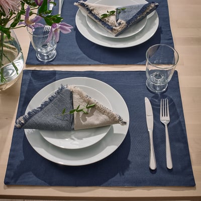 Blue reversible place mats with plates, napkins, cutlery, and glasses.
