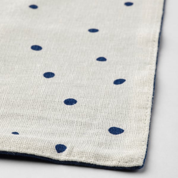 Close-up of reversible cotton-blend place mat with blue dots on creamy side.