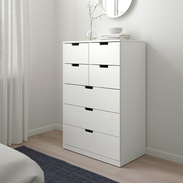 NORDLI chest: 6 drawers, decor, tall, white wall. Black handles, books, vase.