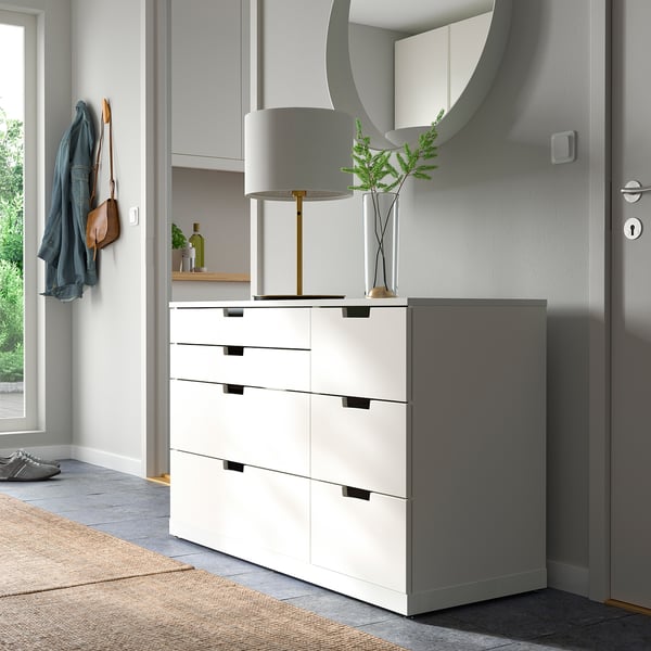 Modern hallway with white NORDLI chest, lamp, mirror, and coat hooks. Chest has four drawers, placed against a wall near a door.