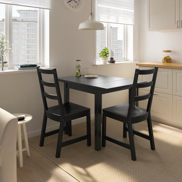 Modern black dining set by city-view window.