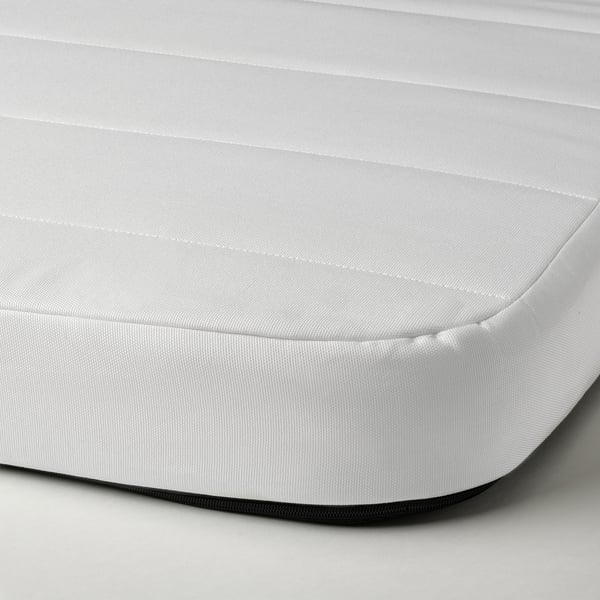 A close-up of a white foam mattress, showing its smooth, covered surface and firm texture.