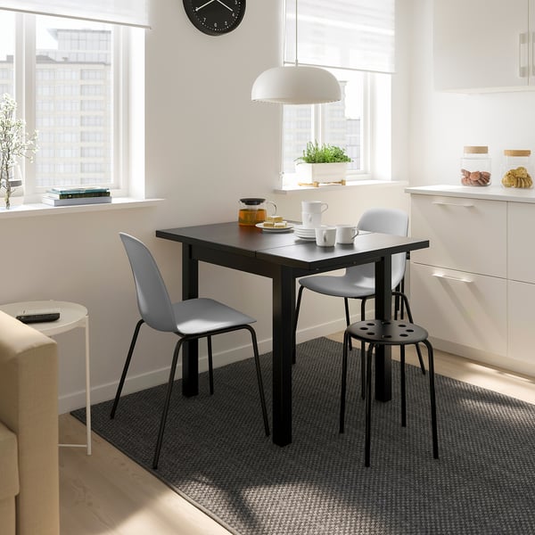 Modern dining area with NYMÅNE light, grey chairs, white cabinets, and natural light.