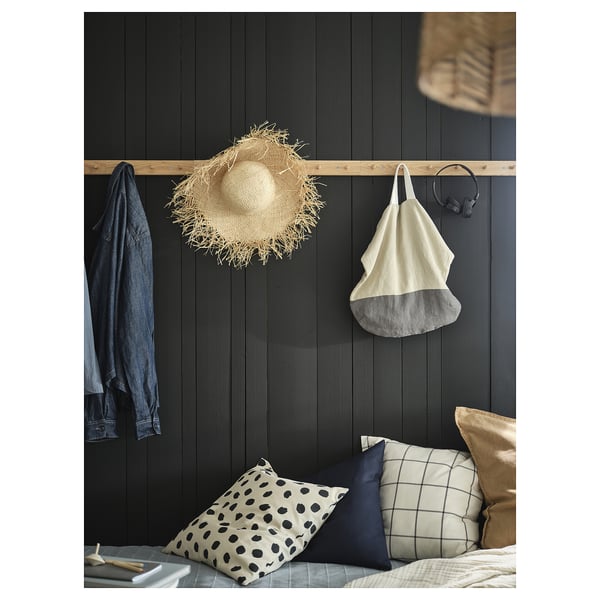 Bedroom with pillows, jacket, hat, bag, headphones, wooden wall.