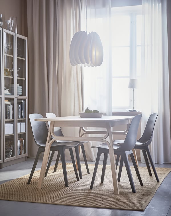 Modern dining area with ODGER grey chairs, light wood table, and large window with sheer curtains.