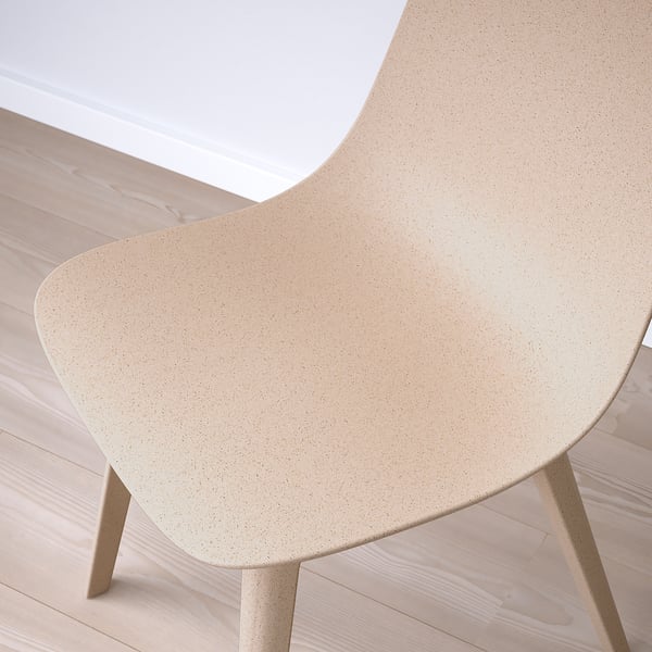 Modern chair showcasing intricate, speckled wooden texture, minimalist design, seamless curves, beige hue.