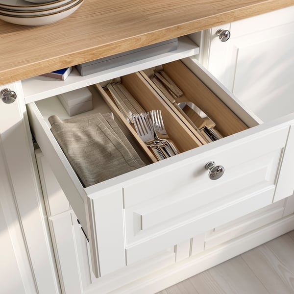Open white kitchen drawer with cutlery tray and folded napkins, showing organised storage.