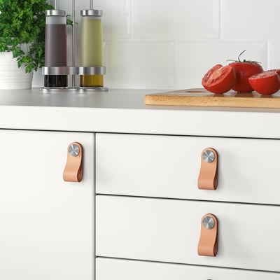 Modern kitchen cabinets with ÖSTERNÄS leather handles. Handles fit doors 16-21 mm thick. Screws included. Fresh tomatoes and herbs on counter.