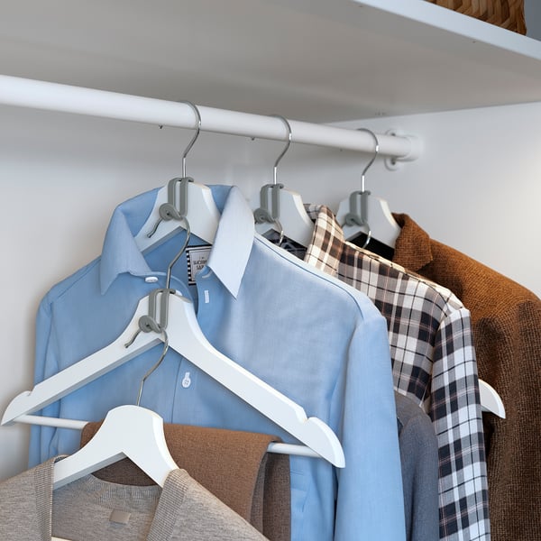 Blue and beige shirts hang on silver hangers in a closet. Two shirts per hanger, white hangers.