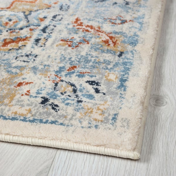 Multicoloured rug with blue, orange, and cream patterns on light wood floor.