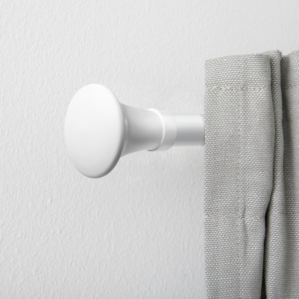 White metal curtain rod finial, trumpet shape, attached to grey curtain.