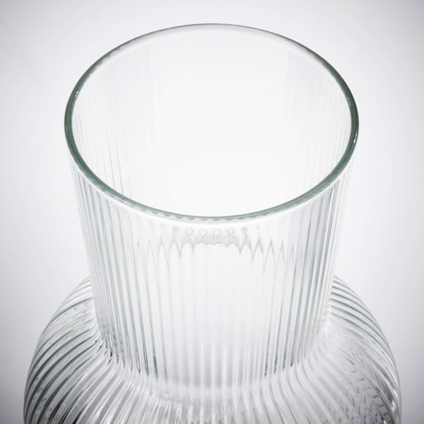 Clear glass vase with vertical ribs, reflecting light, elegant and refined.