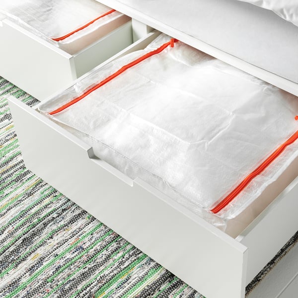A PÄRKLA storage bag in a drawer, holding a white object. The zippered bag stores seasonal items, folds flat when empty.