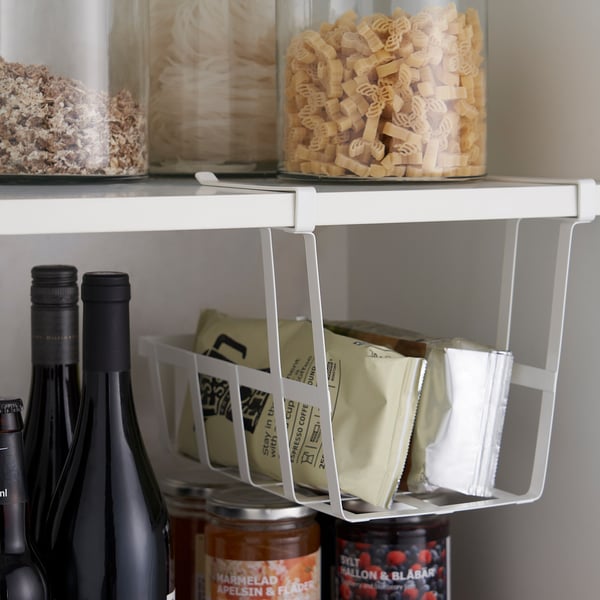 Kitchen shelf with clip-on baskets for additional storage, holding coffee sachets and jars.
