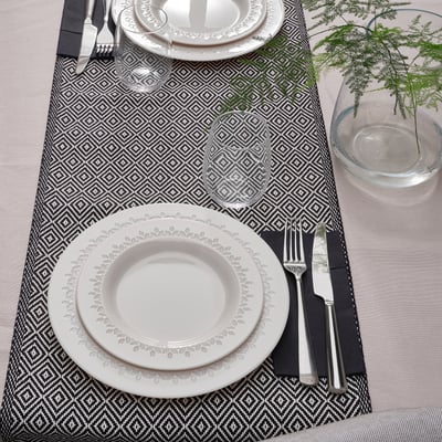 Two place settings with PARADISISK dinnerware, knives, forks, wine glasses, and greenery.