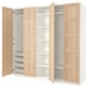 An open IKEA PAX wardrobe with light wood panels and white interiors, showcasing shelves and drawers.