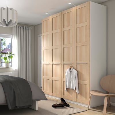 Minimalist bedroom with large oak PAX wardrobe and single shirt. Black heel and grey decor contrast.