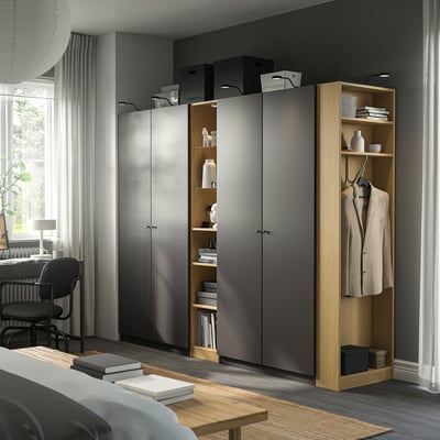 Modern minimalist room with grey PAX wardrobe, beige jacket, desk, and natural light.