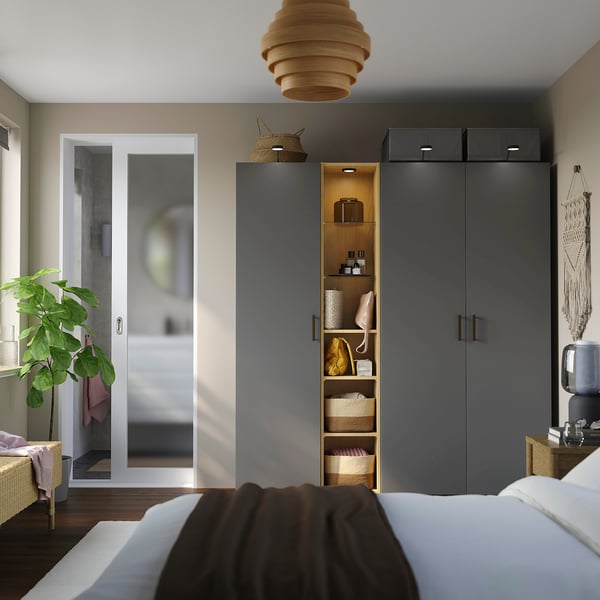 Modern bedroom with large IKEA PAX wardrobe, styled lamp, and plants.