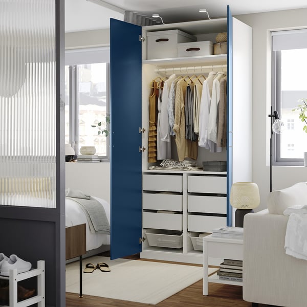 A wardrobe with blue doors opens to show clothes on hangers, folded items, and drawers, illustrating its storage versatility.
