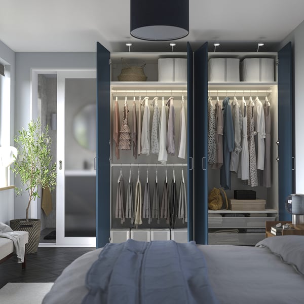 Bedroom with open blue wardrobe, showcasing clothes, shelves, and interior organisation.