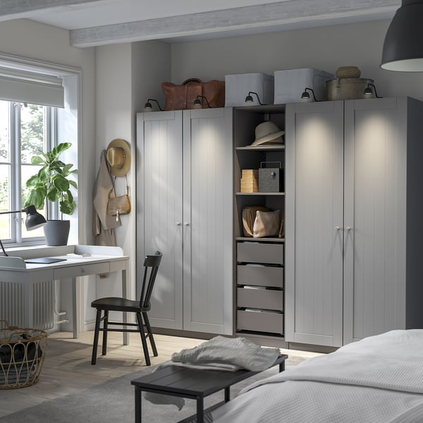 Modern bedroom with large grey PAX wardrobe, desk, and chair. Clothes and accessories neatly organised.