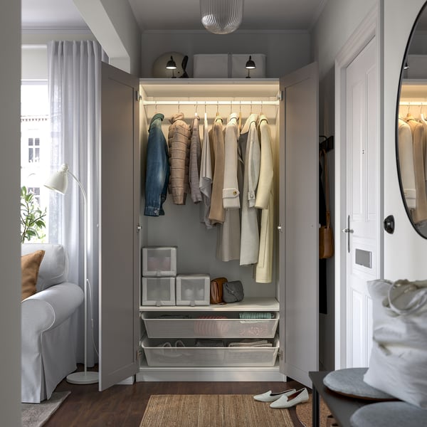 Open wardrobe displaying coats, shelves, and drawers; integrated lighting highlights clothes and storage.