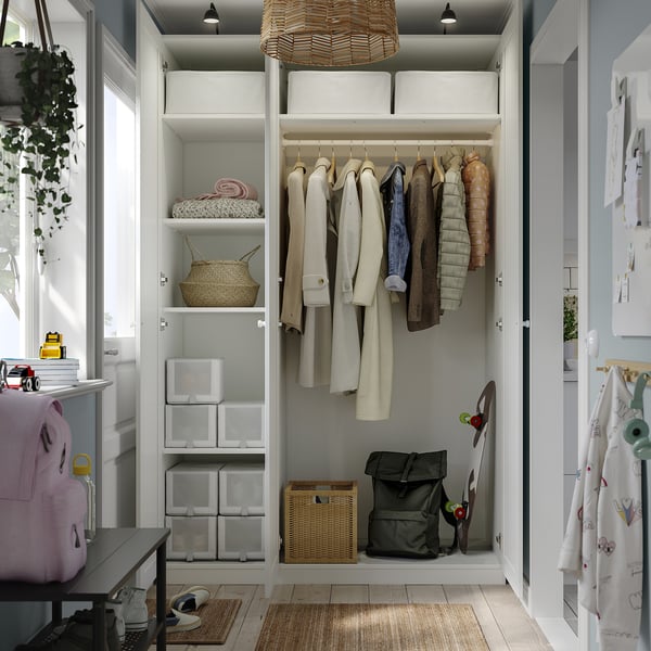 Organised closet with clothes, baskets, coats, backpack, skateboard, good lighting.