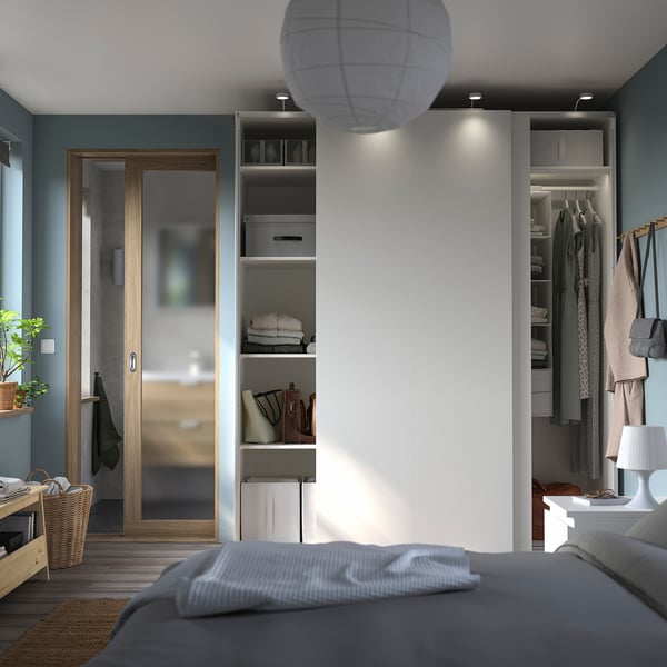 Modern bedroom with grey PAX wardrobe, sliding doors, integrated lighting, and minimalist design.