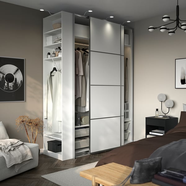 Modern bedroom with PAX wardrobe, sliding doors, open shelves, and integrated lighting.