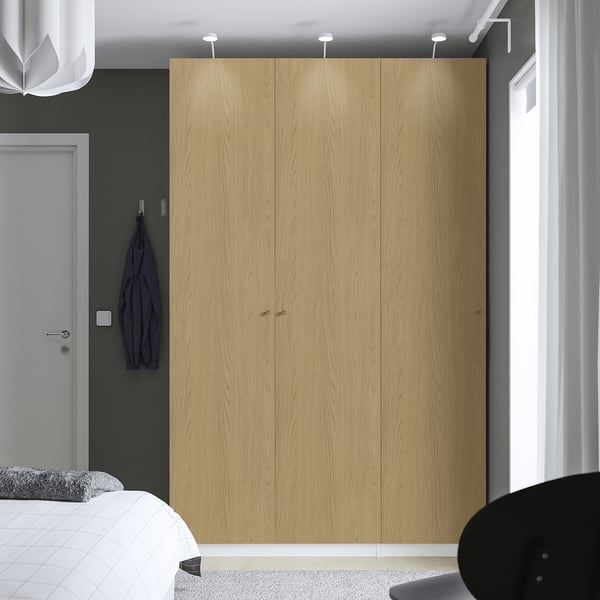 Modern bedroom with light wood PAX wardrobe, blue garment, soft-close hinges, mesh basket.
