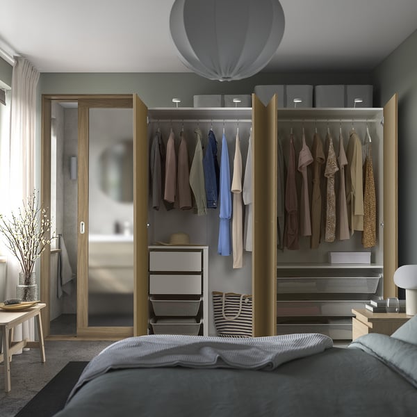 Modern bedroom with wooden wardrobe showcasing clothes, hanging rail, and storage baskets.