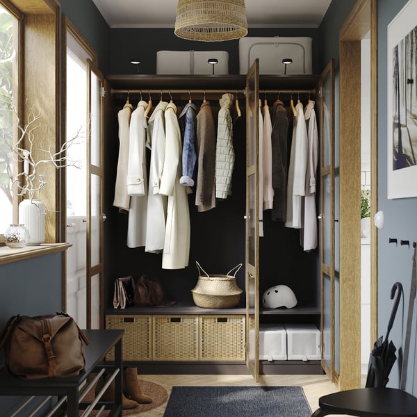 Organized closet with hanging garments, benches, storage baskets, and helmets, showcasing adjustable feet and hinged doors.