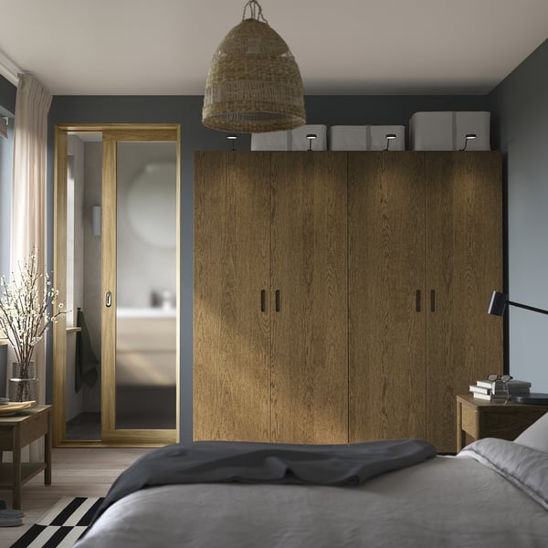 Modern bedroom with tall PAX wardrobe, storage boxes, and pendant light. Grey bed in foreground.