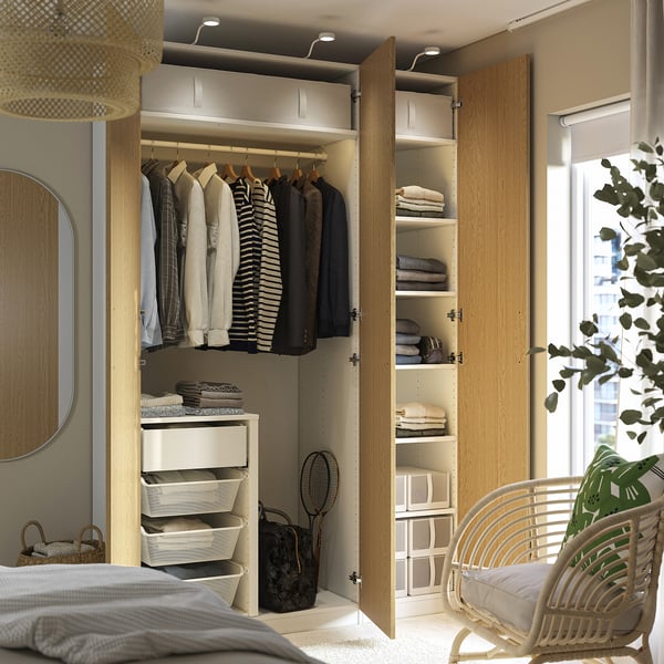 Open wooden wardrobe with clothing, shelves and storage boxes. Integrated lighting illuminates the interior.