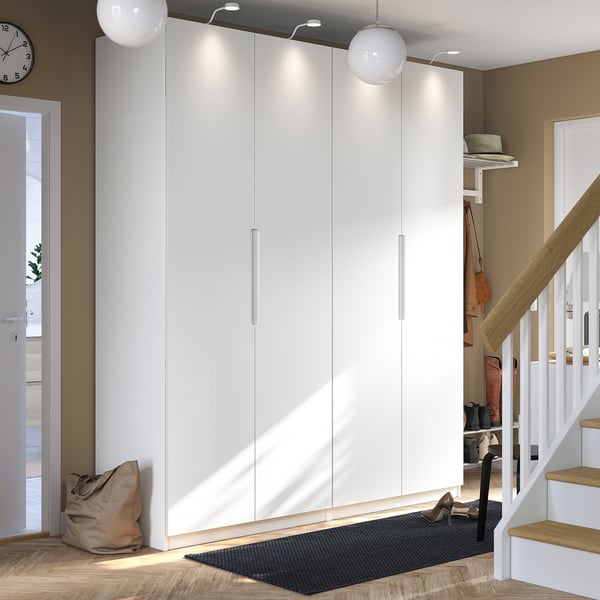 Modern, white, PAX wardrobe with sleek handles. Tall, fits under stairs, brighter than grey rug.