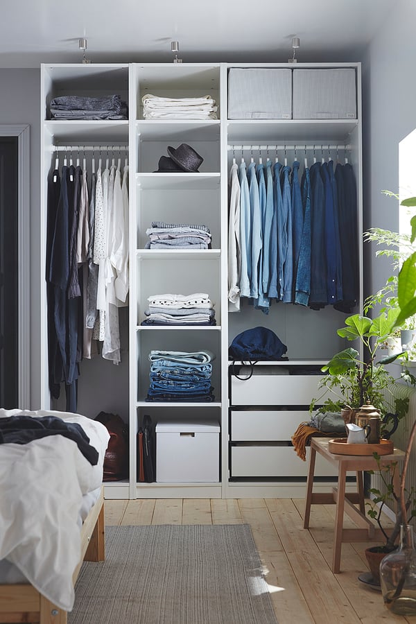 White PAX wardrobe with shelves, hangers, clothes, accessories, and plants.