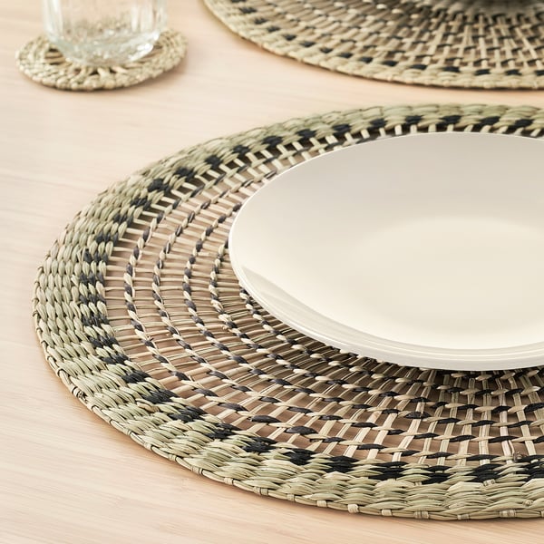 Handwoven round place mat, featuring intricate pattern & natural sedge. Protects table surface, adding rustic charm.