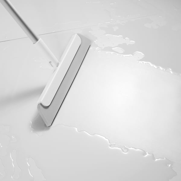 White squeegee with aluminium handle on clean floor, removing water and dirt.